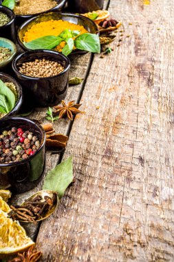 Pişirmek için baharat ve ot seti. Renkli baharatlı küçük kaseler fesleğen, biber, safran, tuz, paprika, zerdeçal. Kırsal ahşap masa arka planında, üst görünüm kopyalama alanı