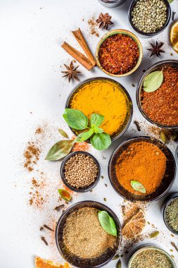 Pişirmek için baharat ve ot seti. Renkli baharatlı küçük kaseler fesleğen, biber, safran, tuz, paprika, zerdeçal. Beyaz taş masa üzerinde arka plan üst görünüm kopyalama alanı