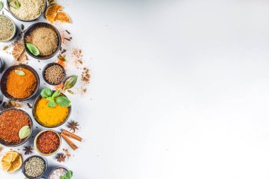 Pişirmek için baharat ve ot seti. Renkli baharatlı küçük kaseler fesleğen, biber, safran, tuz, paprika, zerdeçal. Beyaz taş masa üzerinde arka plan üst görünüm kopyalama alanı