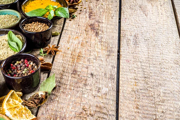 Pişirmek için baharat ve ot seti. Renkli baharatlı küçük kaseler fesleğen, biber, safran, tuz, paprika, zerdeçal. Kırsal ahşap masa arka planında, üst görünüm kopyalama alanı