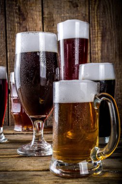 Ahşap bar arka planında farklı türde el yapımı bira. Çeşitli bira bardakları ve kupalar. Bira tatma konsepti