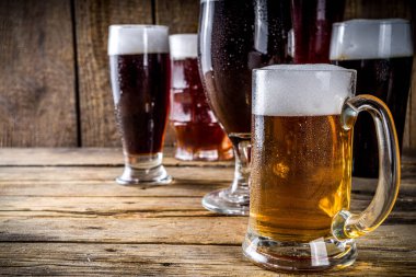 Ahşap bar arka planında farklı türde el yapımı bira. Çeşitli bira bardakları ve kupalar. Bira tatma konsepti