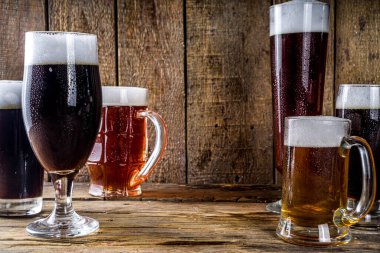 Ahşap bar arka planında farklı türde el yapımı bira. Çeşitli bira bardakları ve kupalar. Bira tatma konsepti