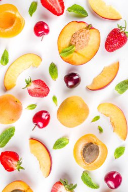 Beyaz arka planda taze meyve ve böğürtlen içeren yaz arkaplanı. Mevsimlik çeşitli meyve ve meyveler. Çilek, kayısı, şeftali dilimleri, kiraz, nane. Düz yatıyordu. Yaz meyveleri konsepti. 