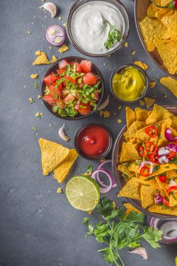 Eritilmiş peynirli cips ve çeşitli geleneksel Meksika sosları, salsa ve jalapeno, koyu gri arka plan fotokopi alanı