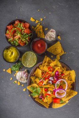 Eritilmiş peynirli cips ve çeşitli geleneksel Meksika sosları, salsa ve jalapeno, koyu gri arka plan fotokopi alanı