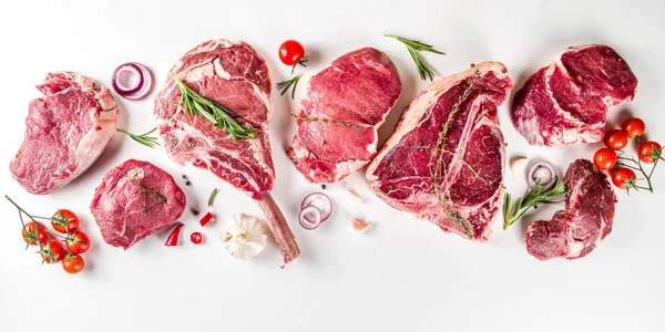 Bir dizi klasik, alternatif çiğ et, dana bifteği - şato mignon, t-bone, tomahawk, striploin, fileto, New York bifteği. Düz görünüm beyaz masa arka planında yatıyordu