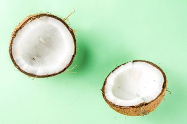 Beyaz arka planda çiğ hindistan cevizi izole edilmiş. Açık yeşil bir masada hindistan cevizlerinin yarısı