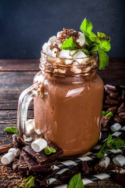 Soslu çikolatalı milkshake, şekerleme ve naneli rendelenmiş çikolata. Bir sürü çikolata, kakao çekirdeği ve çikolata parçacıklarıyla dolu eski bir kırsal ahşap masada.