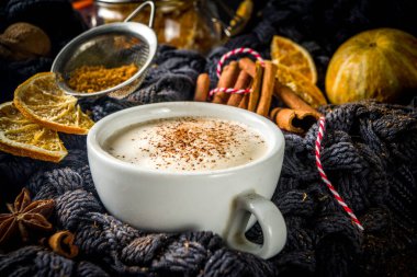 Sonbahar tatlısı, Chai Buttered Rum, Balkabağı Turtası veya Baharatlı Kahve Latte. Geleneksel latte fincanı, baharatları ve eski süveteri olan, kırsal ahşap arka planda rahat bir sonbahar arkaplanı.