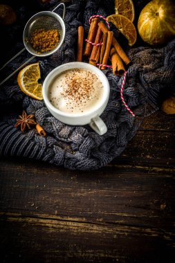Sonbahar tatlısı, Chai Buttered Rum, Balkabağı Turtası veya Baharatlı Kahve Latte. Geleneksel latte fincanı, baharatları ve eski süveteri olan, kırsal ahşap arka planda rahat bir sonbahar arkaplanı.