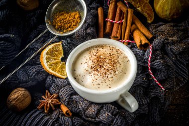 Sonbahar tatlısı, Chai Buttered Rum, Balkabağı Turtası veya Baharatlı Kahve Latte. Geleneksel latte fincanı, baharatları ve eski süveteri olan, kırsal ahşap arka planda rahat bir sonbahar arkaplanı.