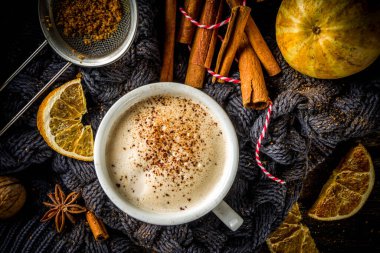 Sonbahar tatlısı, Chai Buttered Rum, Balkabağı Turtası veya Baharatlı Kahve Latte. Geleneksel latte fincanı, baharatları ve eski süveteri olan, kırsal ahşap arka planda rahat bir sonbahar arkaplanı.