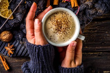 Sonbahar tatlısı, Chai Buttered Rum, Balkabağı Turtası veya Baharatlı Kahve Latte. Sıcak sonbahar arka planı. Geleneksel latte fincanını elinde tut, kırsal ahşap arka planda.