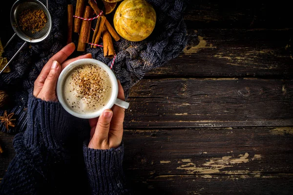 秋の甘いホットドリンク チャイバターラム パンプキンパイまたはパンプキンスパイスコーヒーラテ 素敵な秋の背景 女の子は手で伝統的なラテカップを保持 素朴な木製の背景に — ストック写真
