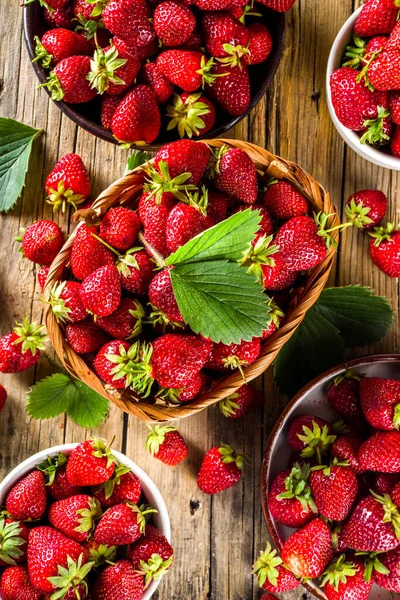 stock image Homemade Organic Ripe Berry Strawberry. Many bowls, baskets with ripe strawberries, with strawberry leaves. On a wooden rustic table.