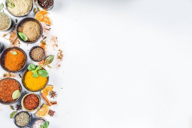 Pişirmek için baharat ve ot seti. Renkli baharatlı küçük kaseler fesleğen, biber, safran, tuz, paprika, zerdeçal. Beyaz taş masa üzerinde arka plan üst görünüm kopyalama alanı