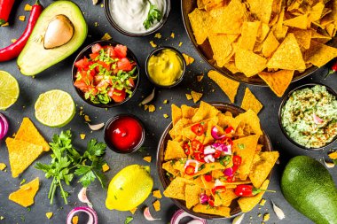 Eritilmiş peynirli cips ve çeşitli geleneksel Meksika sosları, salsa ve jalapeno, koyu gri arka plan fotokopi alanı