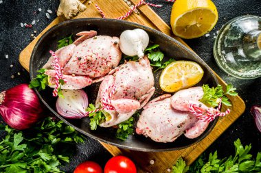 Sağlıklı beslenme öğle yemeği konsepti. Siyah taş bir masa üzerinde pişirmek için baharatlı, otlu, sebzeli, zeytinyağlı tam üç bıldırcın.