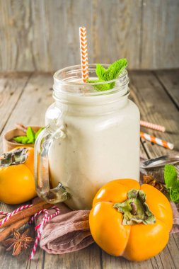 Sonbahar sağlıklı içecekler ve aperatifler. Baharatile Sonbahar mevsimsel hurmaya smoothie - tarçın, anason, nane yaprakları ile. Rustik ahşap arka planda,