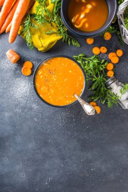 Lezzetli ev yapımı kremalı havuç çorbası. Sebze havuç çorbası püresi koyu gri masada taze havuçlarla kopyalanıyor.