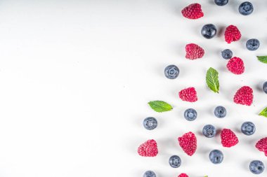 Beyaz zemin üzerinde taze yaban mersini ve ahududu dolu düz bir desen.