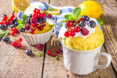Limonlu kek. Mikrodalgada tatlı yaz tatlısı. Taze böğürtlenli ve çırpılmış kremalı limonlu turtalar ahşap arka planda.