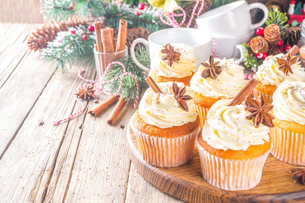 Homemade Christmas sweet baking. Christmas Eggnog Cupcakes with sugared spices, wooden background with xmas decoration