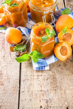 Farklı kavanozlarda ev yapımı kayısı reçeli, ahşap arka planda taze organik kayısılar fotokopi alanı