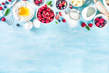 Böğürtlenli kek tarifi. Yaz pişirme arka planında çeşitli böğürtlenler, pişirme malzemeleri, aletler ve çatallar, açık mavi güneş ahşap arka planda düz bir zemin oluşturur.