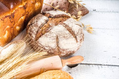 Çeşitli ekmek setleri. Birçok farklı buğday, tahıl ve çavdar ekmeği çavdar ve buğday, un ve fırıncı aletleriyle beyaz ahşap arka planda.