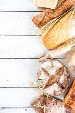 Çeşitli ekmek setleri. Birçok farklı buğday, tahıl ve çavdar ekmeği çavdar ve buğday, un ve fırıncı aletleriyle beyaz ahşap arka planda.