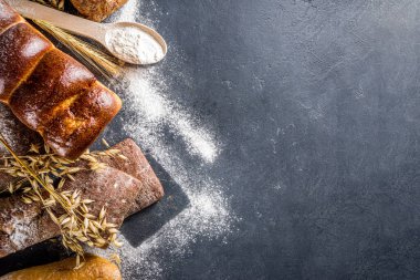 Çeşitli ekmek setleri. Birçok farklı buğday, tahıl ve çavdar ekmeği çavdar ve buğday, un ve fırıncı aletleriyle beyaz ahşap arka planda.