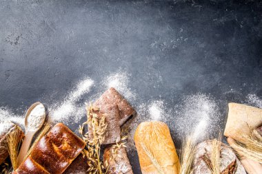 Çeşitli ekmek setleri. Birçok farklı buğday, tahıl ve çavdar ekmeği çavdar ve buğday, un ve fırıncı aletleriyle beyaz ahşap arka planda.