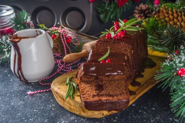 Şenlikli arka planda çikolatalı zencefilli kek. Geleneksel zencefilli kek, koyu çikolata soslu, kızılcık ve biberiyeli, Noel süslemeli masa, kopyalama alanı