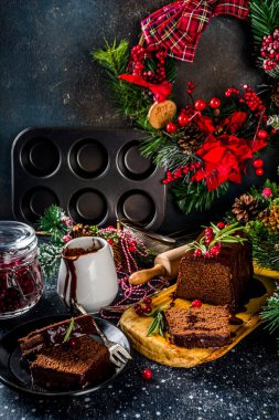 Şenlikli arka planda çikolatalı zencefilli kek. Geleneksel zencefilli kek, koyu çikolata soslu, kızılcık ve biberiyeli, Noel süslemeli masa, kopyalama alanı