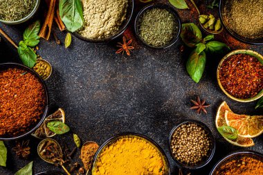 Pişirmek için baharat ve ot seti. Renkli baharatlı küçük kaseler fesleğen, biber, safran, tuz, paprika, zerdeçal. Siyah taş tablo üzerinde üst görünüm kopyalama alanı