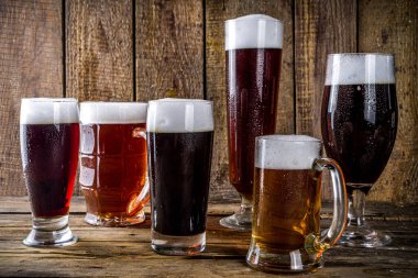 Ahşap bar arka planında farklı türde el yapımı bira. Çeşitli bira bardakları ve kupalar. Bira tatma konsepti