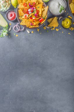 Eritilmiş peynirli cips ve çeşitli geleneksel Meksika sosları, salsa ve jalapeno, koyu gri arka plan fotokopi alanı