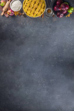 Sonbahar elmalı turta pişirme geçmişi. Çiğ geleneksel elmalı turta, fırın malzemeleri ve çatallar, siyah beton arka plan kopyalama alanı ile pişirme arka planı 