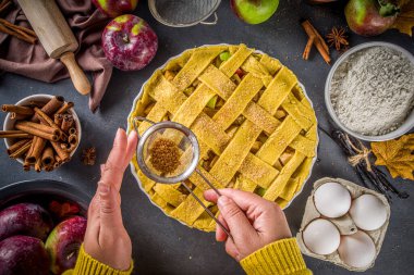 Sonbahar elmalı turta pişirme geçmişi. Çiğ geleneksel elmalı turta, pişirme malzemeleri ve çatal bıçak, beyaz ahşap arka plan fotokopi alanı, kız elleri pasta baharatları serpiyor.