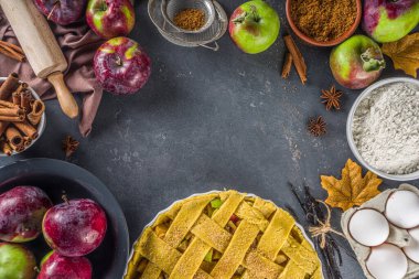 Sonbahar elmalı turta pişirme geçmişi. Çiğ geleneksel elmalı turta, fırın malzemeleri ve çatallar, siyah beton arka plan kopyalama alanı ile pişirme arka planı 