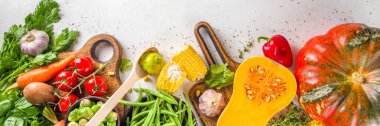 Sonbahar aşçılığı. Organik güz hasadı sebzeleri, geleneksel Şükran Günü yemeği pişirmek için çiğ vegan malzemeleri ve beyaz arka planda düşen yiyecekler.