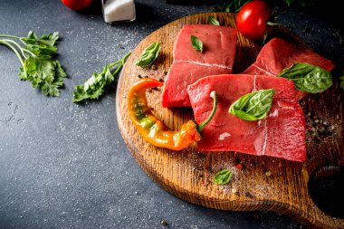 Baharat ve otlarla pişirme masasında çiğ biftek, arka planda karanlık kopya alanı