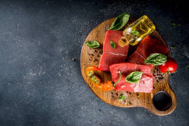 Baharat ve otlarla pişirme masasında çiğ biftek, arka planda karanlık kopya alanı