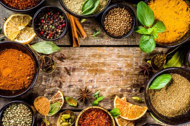 Pişirmek için baharat ve ot seti. Renkli baharatlı küçük kaseler fesleğen, biber, safran, tuz, paprika, zerdeçal. Kırsal ahşap masa arka planında, üst görünüm kopyalama alanı