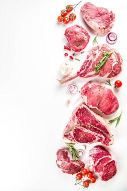 Bir dizi klasik, alternatif çiğ et, dana bifteği - şato mignon, t-bone, tomahawk, striploin, fileto, New York bifteği. Düz görünüm beyaz masa arka planında yatıyordu
