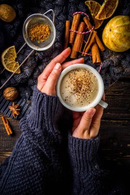 Sonbahar tatlısı, Chai Buttered Rum, Balkabağı Turtası veya Baharatlı Kahve Latte. Sıcak sonbahar arka planı. Geleneksel latte fincanını elinde tut, kırsal ahşap arka planda.