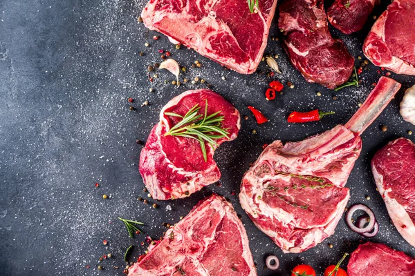 Set of various classic, alternative raw meat, veal beef steaks - chateau mignon, t-bone, tomahawk, striploin, tenderloin, new york steak. Flat lay top view on gray stone cutting table