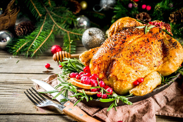 Традиционное Рождество и День благодарения жареная целая курица с фруктами и розмарином. Сельский деревянный рождественский стол, с ветками елки и украшения копировать пространство